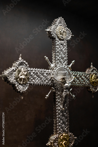 Silver crucifix in medieval Gothic style exposed with a background in shades