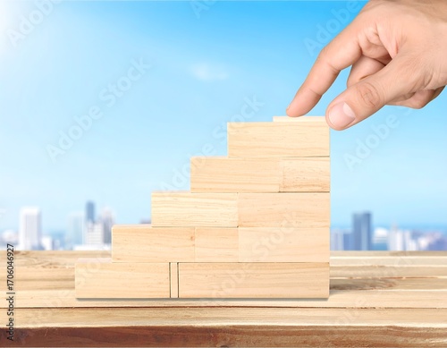 Hand placing wooden block on a staircase, symbolizing growth