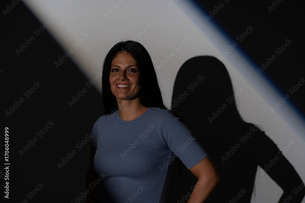 Naklejka premium Low key portrait of smiling mature woman with geometric gobo shadow on dark background