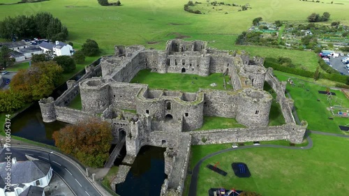 Aerial view of  the medieval ruins of Beaumaris Castle and the coastal town of Beaumaris on the Isle of Anglesey in Gwynedd off the north Wales coast. The castle dates from around 1295.