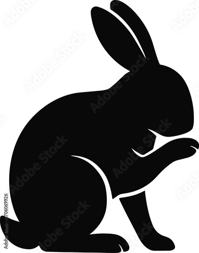 Minimal vector silhouette, grooming rabbit licking paw, seated, side profile, solid black