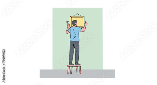 Man standing on a stool using a hammer and nail to hang a picture frame on a wall.