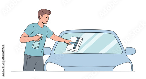Young man in a blue tshirt cleaning a car windshield with a squeegee and spray bottle.