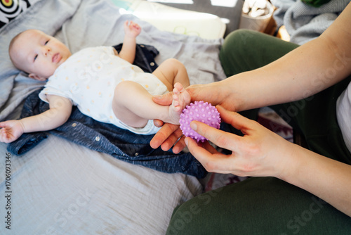 Close up Father massages baby's legs with massage ball. Healthy massage. Massage therapist. Sensory tactile activities. Massage textured balls for kids. Earlier development. Focus picked.