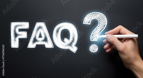 Hand writing faq with chalk on a dark blackboard, representing frequently asked questions