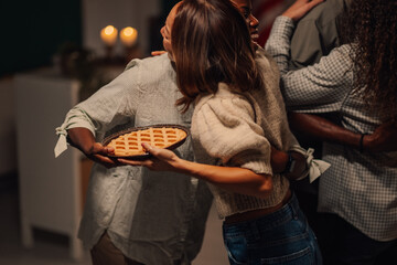 Friends bringing pie and hugging at thanksgiving dinner