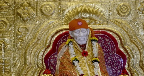 Sai Baba is seated peacefully in the temple, radiating a divine positive aura that fills the atmosphere with serenity and devotion