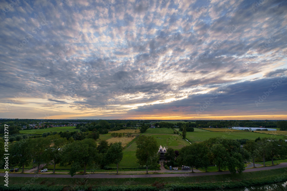 Obraz premium Breathtaking balcony view overlooking the lush green fields of Holland's countryside during a stormy summer sunset near Amsterdam, Netherlands