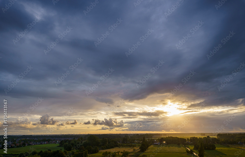 Obraz premium Breathtaking balcony view overlooking the lush green fields of Holland's countryside during a stormy summer sunset near Amsterdam, Netherlands