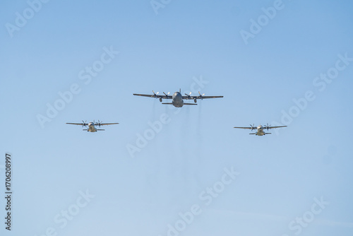 C-130 Hercules aircraft flying in formation over clear blue skies during a day of military training