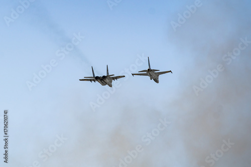 Fighter jets soar through the sky leaving trails of smoke above the clouds in a display of power and agility during a training mission