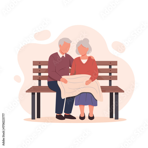 Elderly couple sitting on a park bench sharing a blanket.