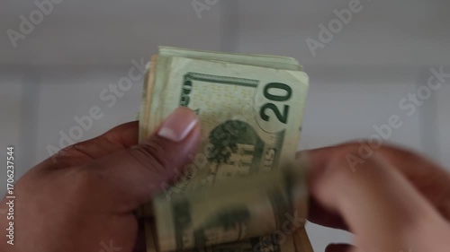 Cashier counting one hundred, twenty and five dollar bills