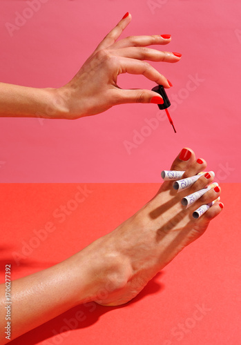 Woman painting red toenails with £20 notes as toe separators