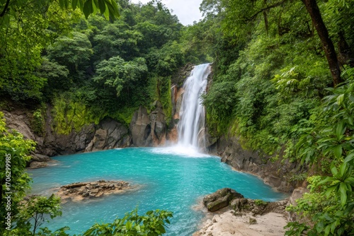 Majestic waterfall cascading into vibrant turquoise pool in lush rainforest