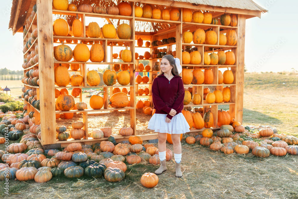 Φωτογραφία Cute girl in sweater and skirt stands near terrace at fall market, harvesting pumpkin festival