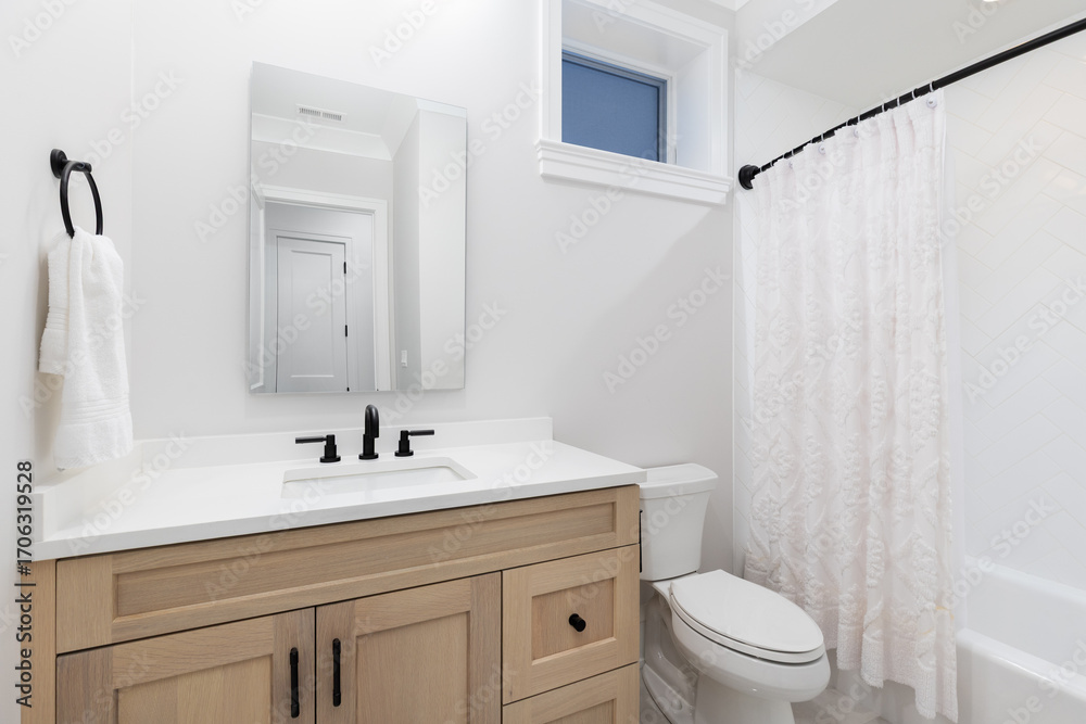 Obraz premium A bathroom with a white oak cabinet, black faucet on a white marble countertop, and white herringbone tile shower.