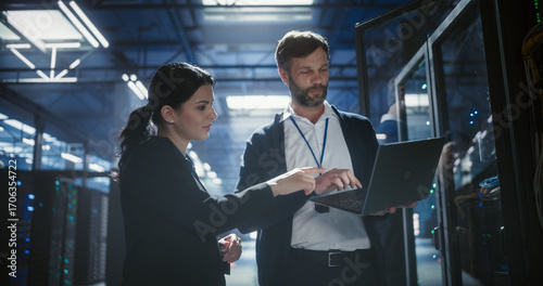 Two server specialists talk and work in data center.