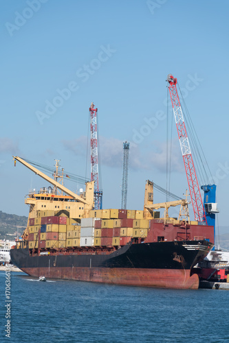 Unloading large ocean container vessel, sea transport of containers, container shipping, ship charter, international transportation, port of Trapani, Sicily, Italy