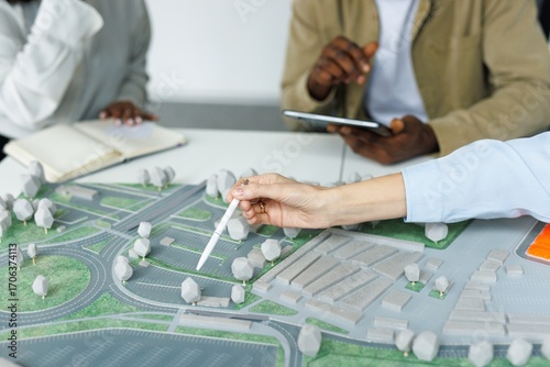 Partial architects pointing on area model during meeting at desk