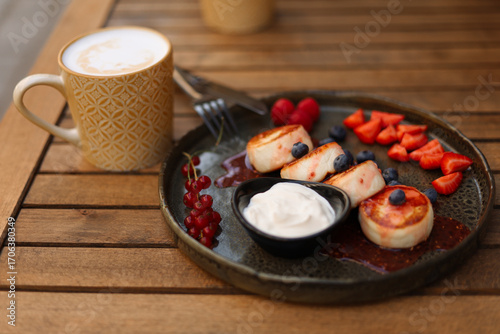 Cheesecakes with strawberries, blueberries, cranberries and sour cream in a black plate.