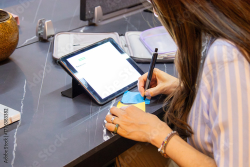 Female office worker making handwritten notes on post its