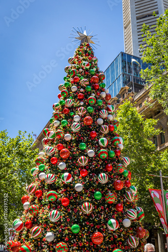 Canvas Print A large, elaborately decorated Christmas tree stands tall in the city of Sydney, Australia, against a backdrop of blue sky and nearby buildings