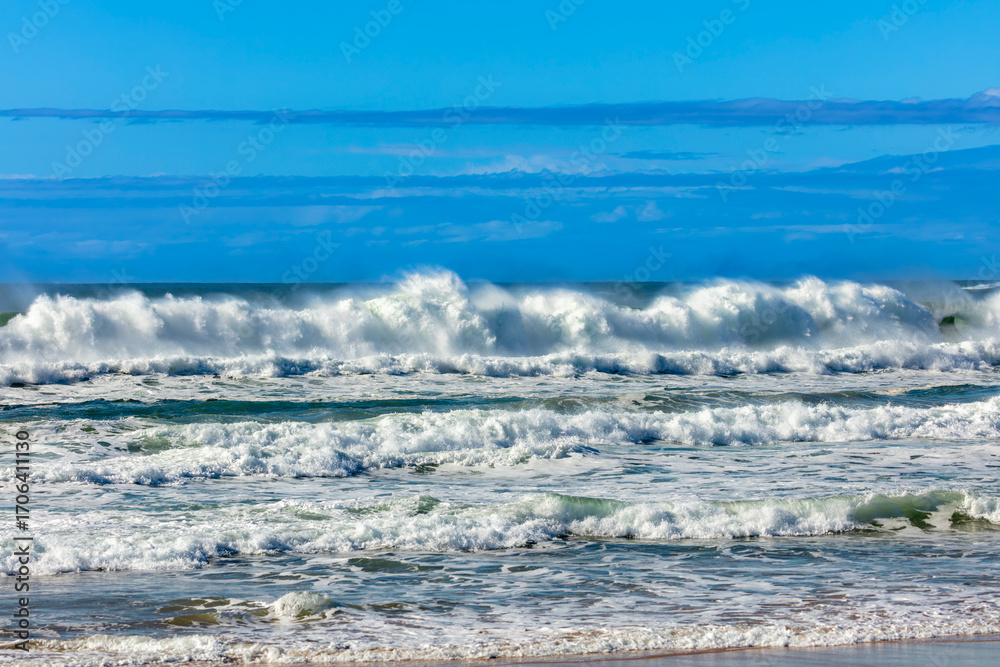 Fototapeta premium Photograph of waves from the Tasman Sea crashing onto Jones Beach against a blue sky near the town of Kiama Downs in the Illawarra region on the south coast of NSW, Australia.