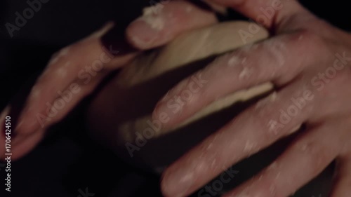Hands kneading dough – Baker’s hands kneading soft dough on table in warm light, homemade bread preparation process