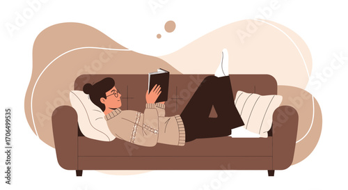 Woman Reading A Book Lying Down, Relaxing On A Sofa At Home In Peaceful Position