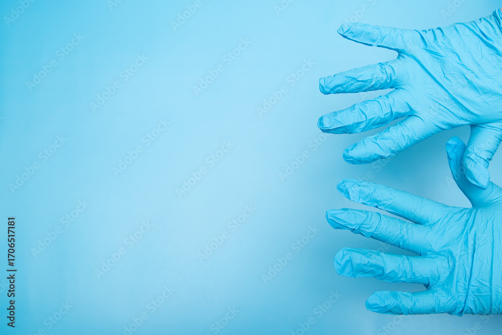 Fototapeta premium Hands in blue gloves on a blue background, space for text, a place for a picture