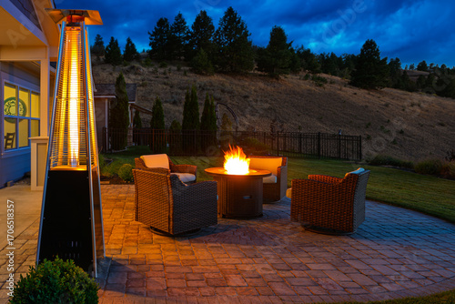 Pyramid patio heater and flaming fire pit warming a residential outdoor deck with seating on a cold evening.