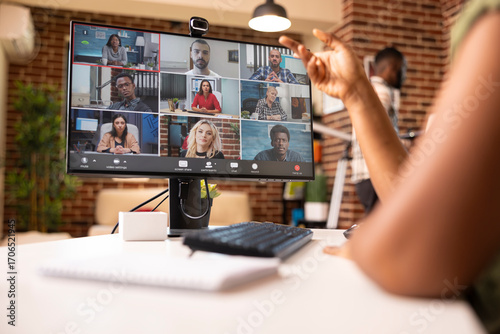 Professional individual in apartment, leading brainstorming session with remote coworkers on desktop monitor. African american entrepreneur managing virtual team and planning business growth.
