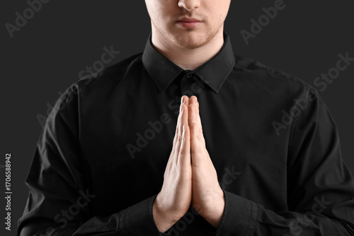 Young man praying on dark b...