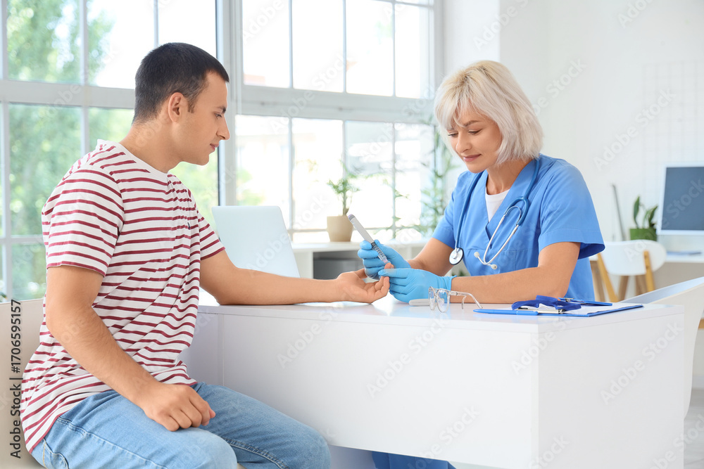 Obraz premium Female endocrinologist measuring blood sugar level of man at table in clinic