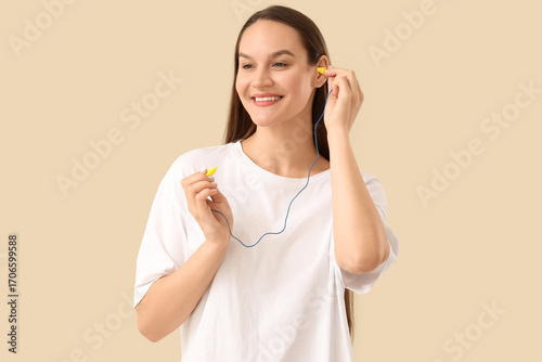 Young woman putting ear plu...
