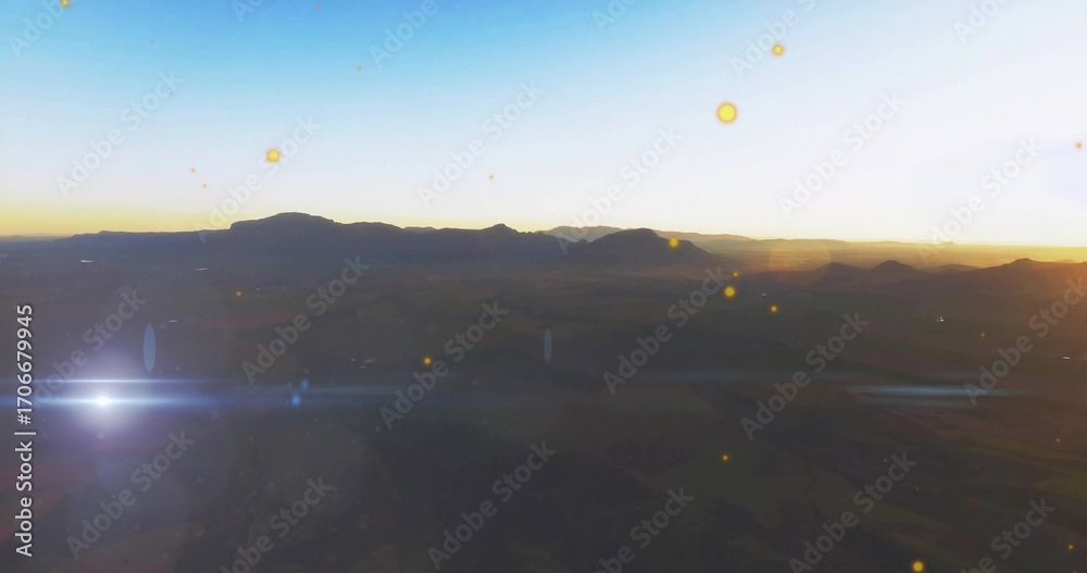 Obraz premium Showing dark mountain ridge against bright sunrise horizon, with valley textures and lens flare