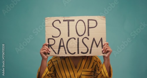 Hispanic Woman hold poster Stop Racism look at camera serious racial morality society peace matter human text words can kill torture close up slow motion