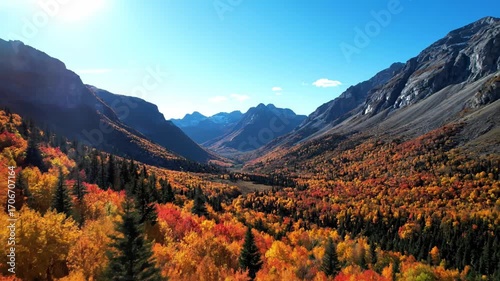 Aerial footage of a pristine, remote mountain range covered in autumn colors under a bright, sunny sky from above, vibrant, calm
