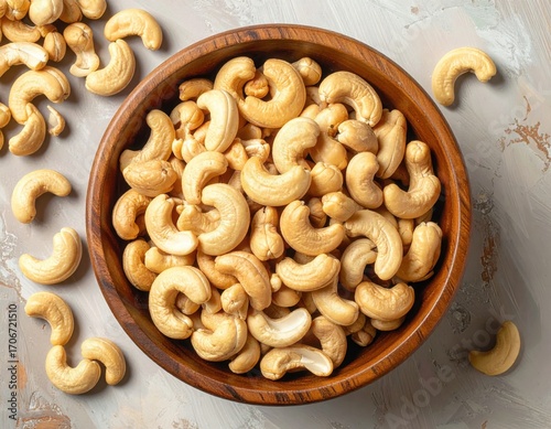 Roasted cashew nuts in wooden bowl with pile of cashew nuts on the table. top view.