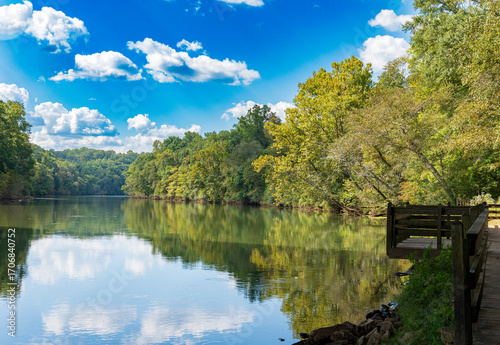 Background of calm river and its reflection at Roswell Riverwalk Boardwalk, a 7-mile off-road path runs along the Chattahoochee River in Roswell, Georgia, North Fulton County. Walking path along river