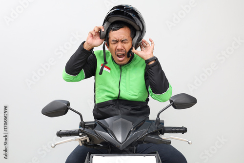 Stressed asian online driver man releasing his helmet while sitting on motorcycle. Isolated on white background