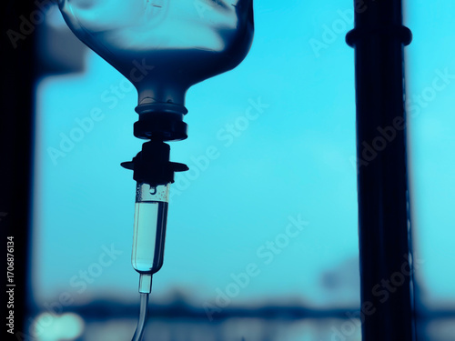 Medical infusion pump with digital screen displaying flow rate in a hospital room. Pediatric patient resting in bed in the background. Healthcare and intravenous therapy concept.