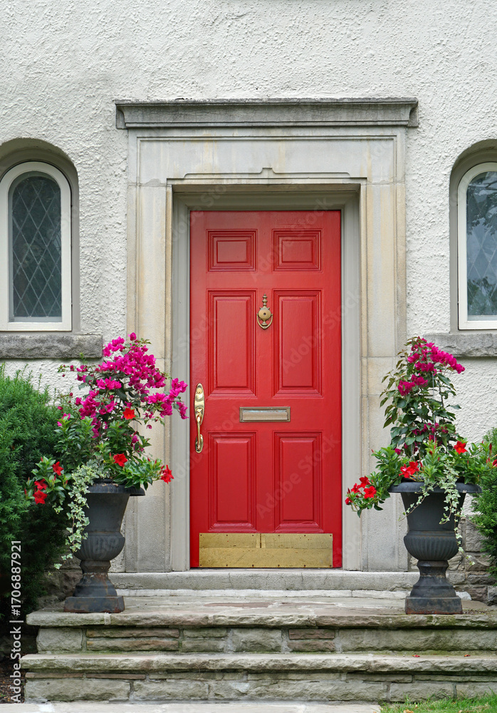 Fototapeta premium stuccoed house with bright red front door and flowers in pots