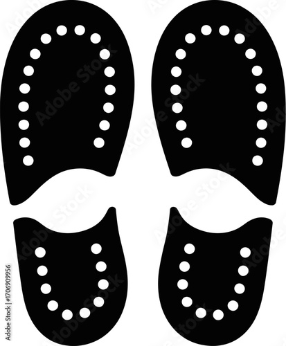 Black shoe soles with white stitching on a light gray background