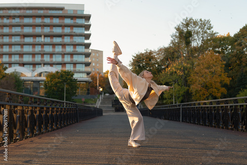 Young woman performing a gymnastic pose on a city bridge