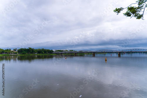 Wallpaper Mural A lone boat glides on the Huong 's River under a cloudy sky, with the historic Truong Tien Bridge in the background, in Hue, Vietnam. Torontodigital.ca