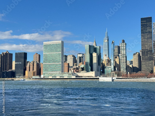 The United Nations Headquarters in New York, the Secretariat Building and the General Assembly Building, seen across the East River. Blue sky.
From Gantry Plaza State Park in Long Island City.