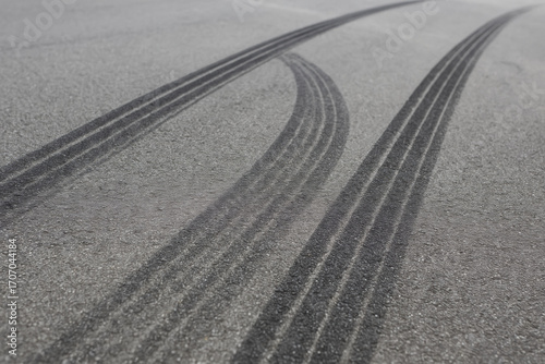Tire marks asphalt surface create striking visual of speed and motion, showcasing aftermath of vehicle rapid movement. dark lines contrast sharply with gray pavement, evoking sense of excitement
