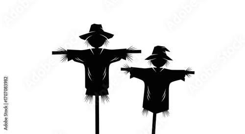 Silhouette of two scarecrows with hats and outstretched arms, standing in a field.